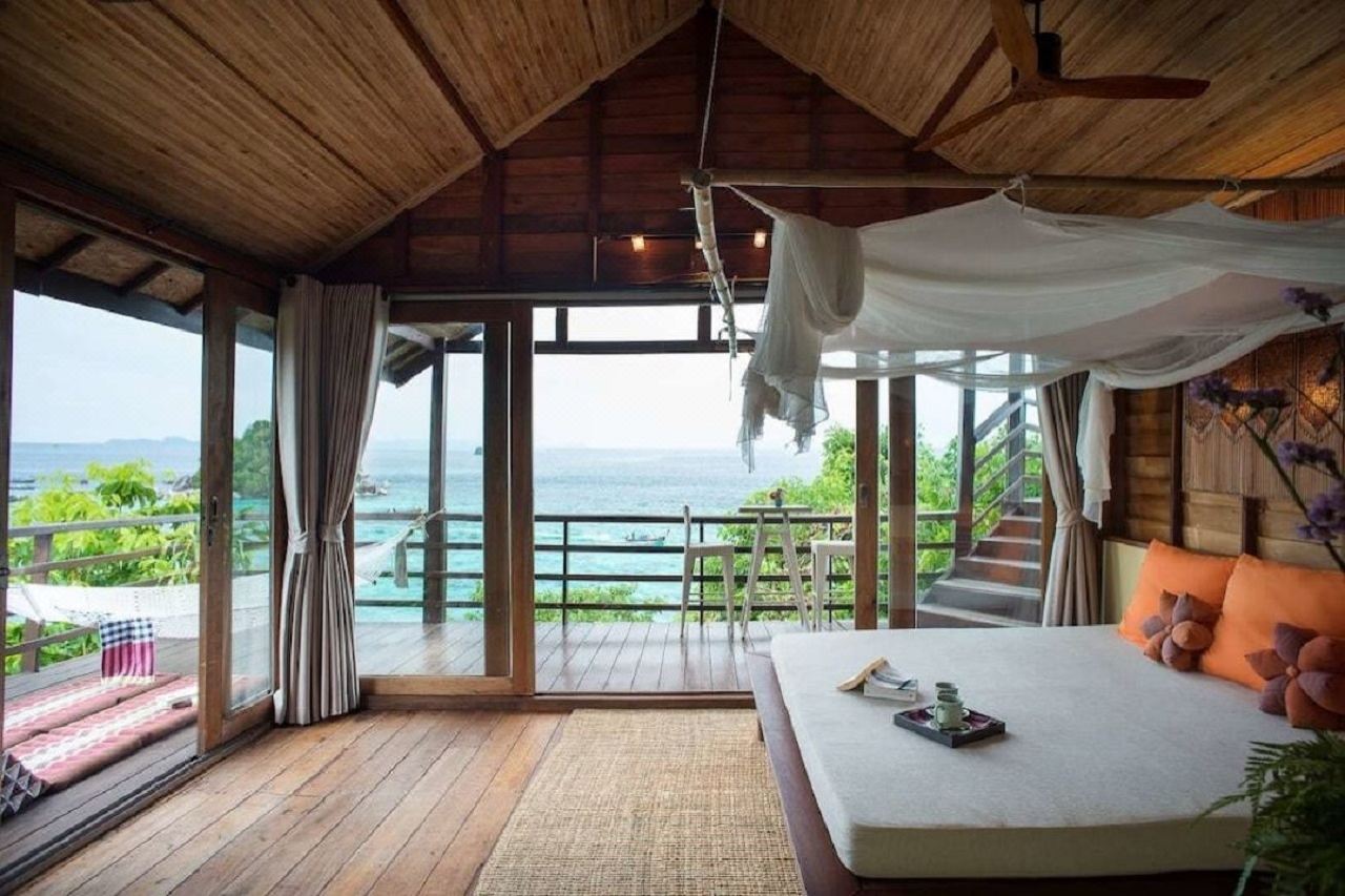 High wooden-ceiling villa bedroom with daybed and sea view