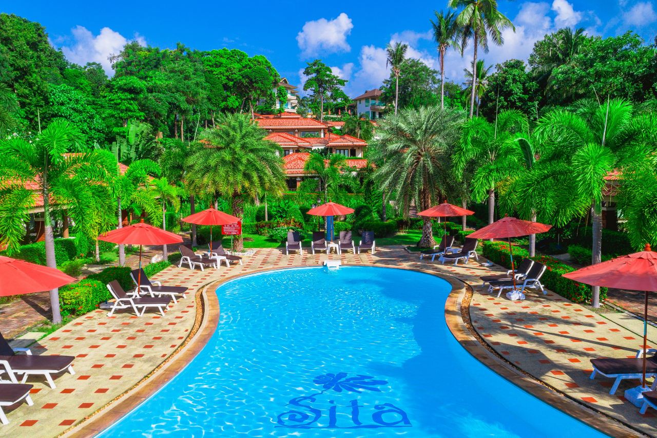 Garden swimming pool with terracotta-roofed buildings and palm trees