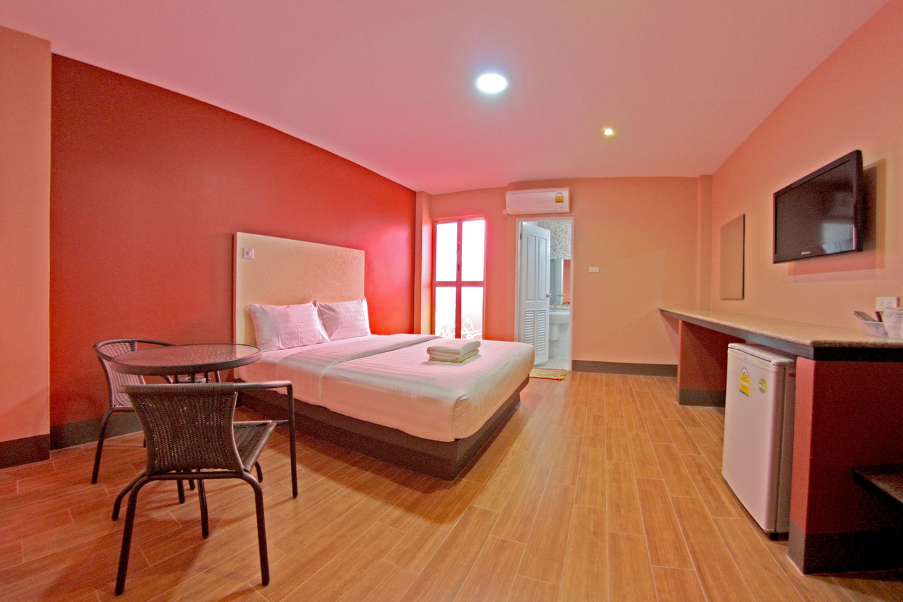 Spacious guest room with wood-look floor, warm orange walls, balcony and fridge