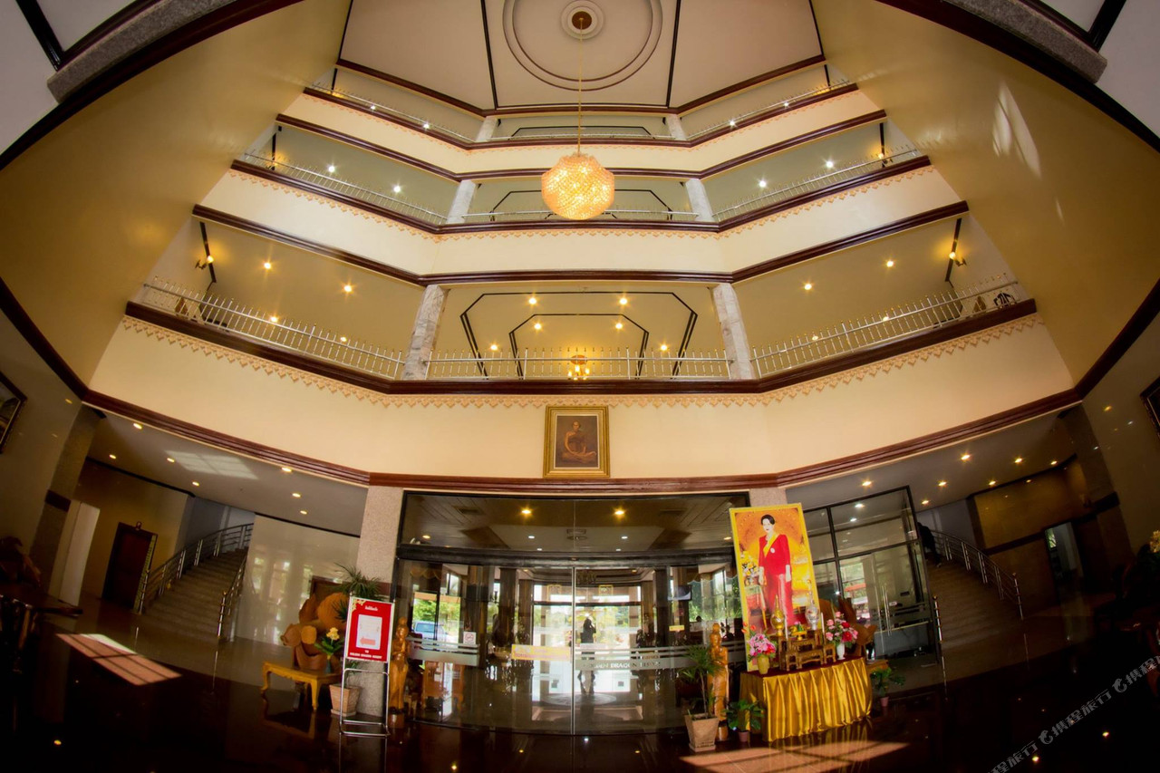 Octagonal multi-floor lobby atrium with a central chandelier and royal portrait