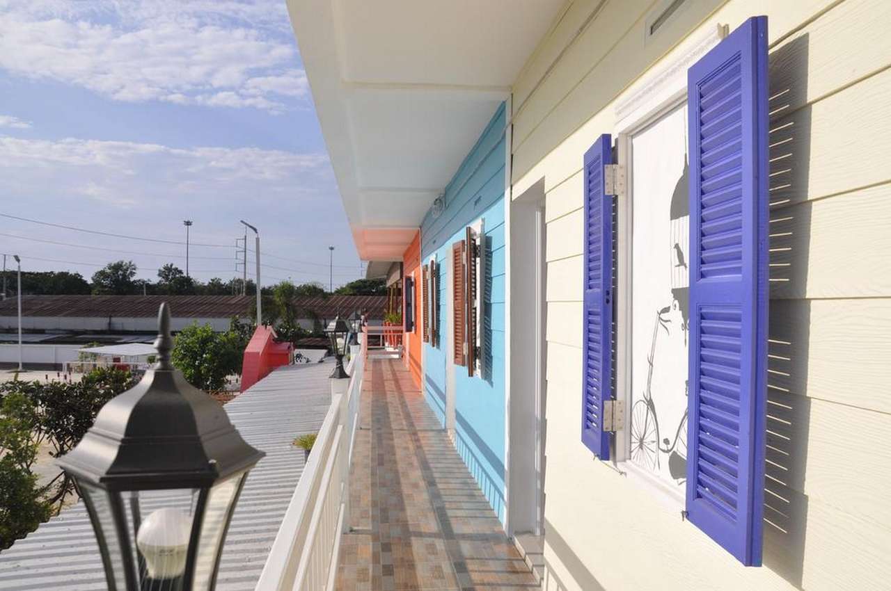 Pastel-painted terrace walkway with purple louvered shutters at Heyday Singburi