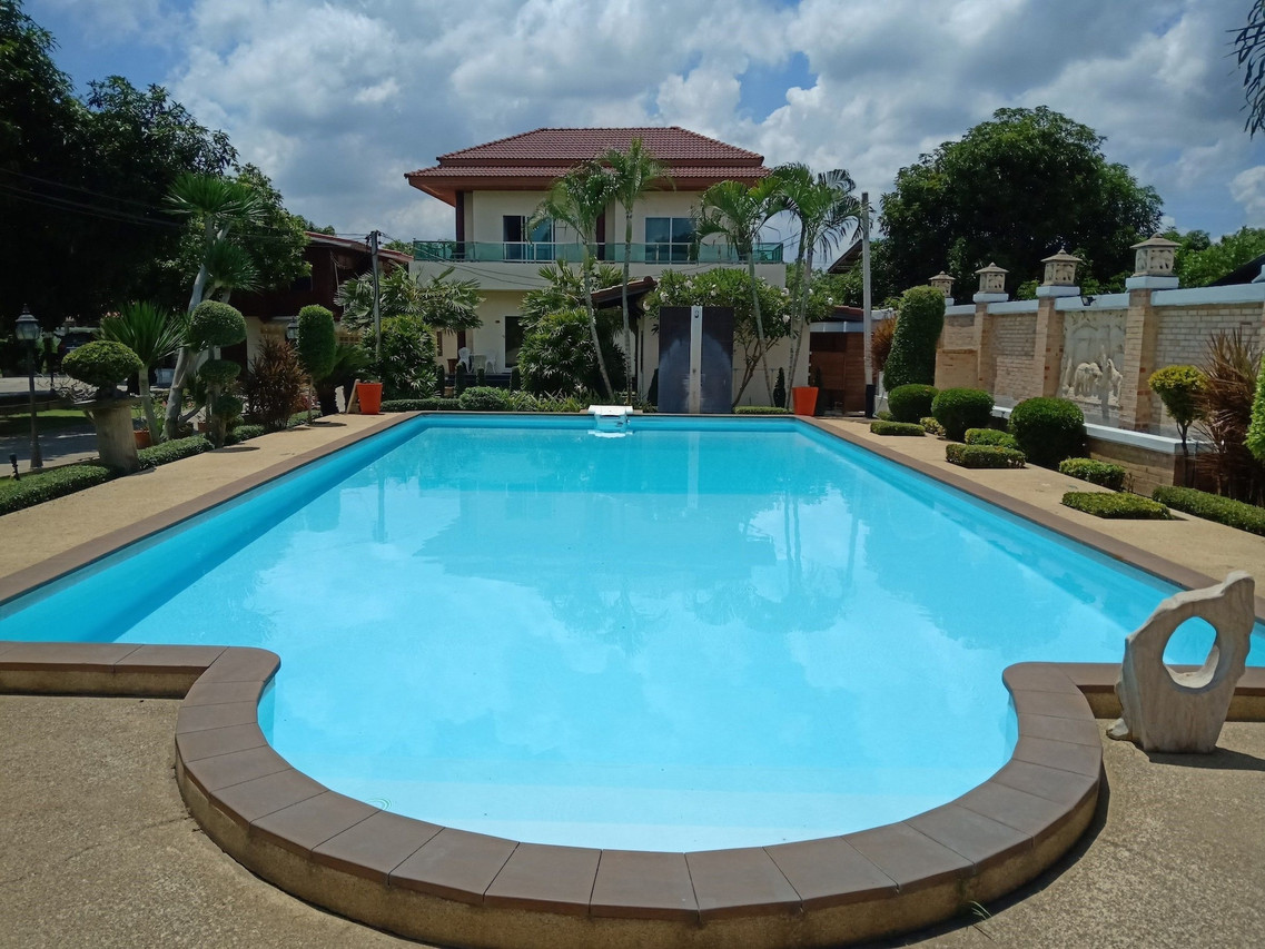 Outdoor pool in front of the two-storey Sumali Villa house with a red-tiled roof