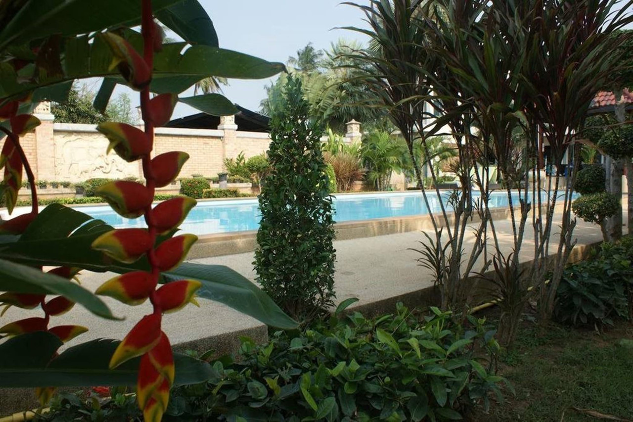 Swimming pool seen through the green garden with tropical plants and flowers