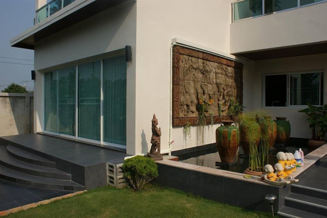 Terrace with carved sandstone Thai-Khmer relief panel, a lotus pond and ceramic jars