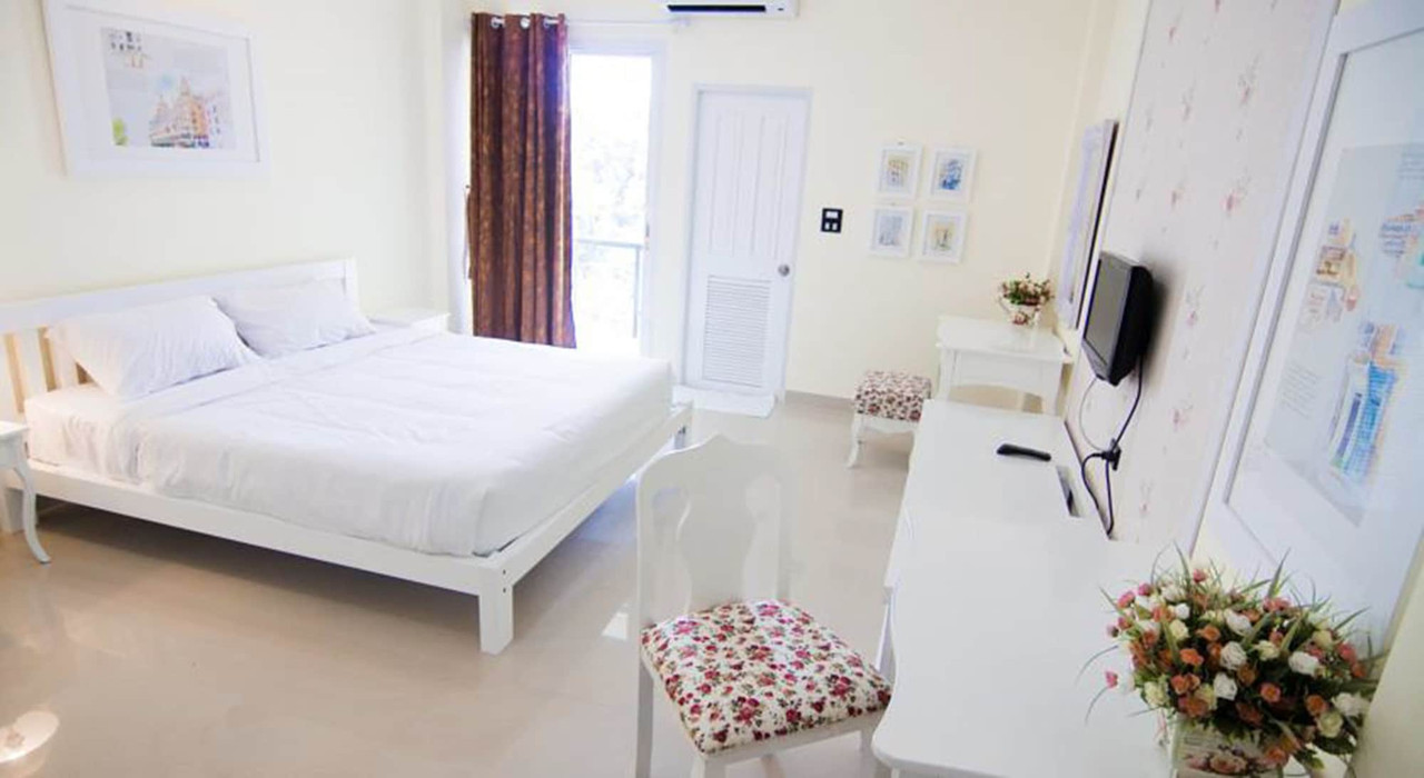 Bright white guest room with white wood furniture and a private balcony at Boonsiri Boutique Hotel