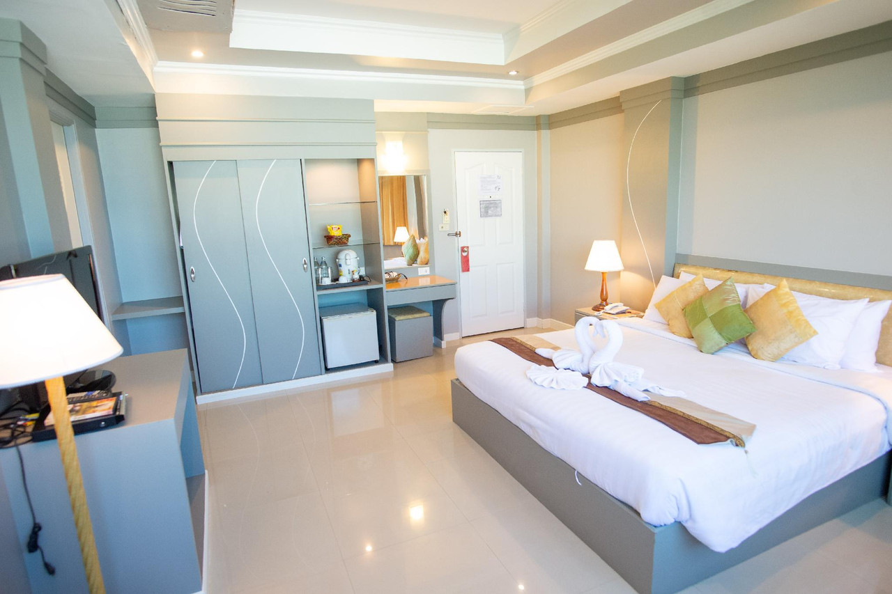 ห้อง Deluxe ของ Phrom Phiman Hotel เตียงพับผ้าเป็นรูปหงส์ โทนสีฟ้าอ่อน