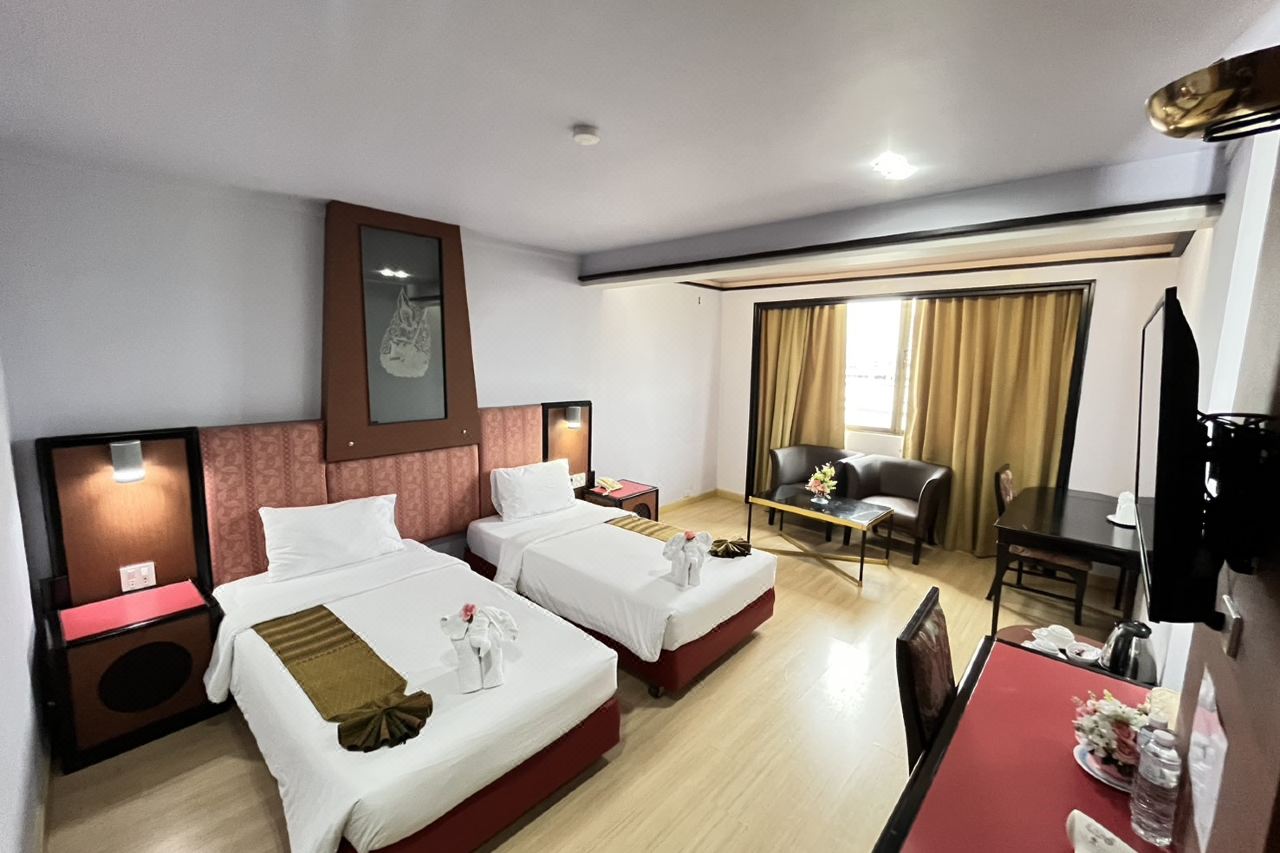 Twin-bed guest room with a sitting area and elephant-folded towels