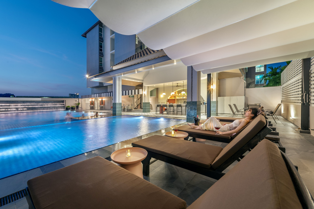 Rooftop pool and sun loungers at dusk with the hotel building behind