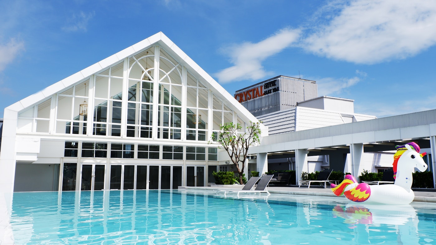 Rooftop pool at Crystal Hotel Hat Yai with the hotel sign and Hat Yai skyline behind