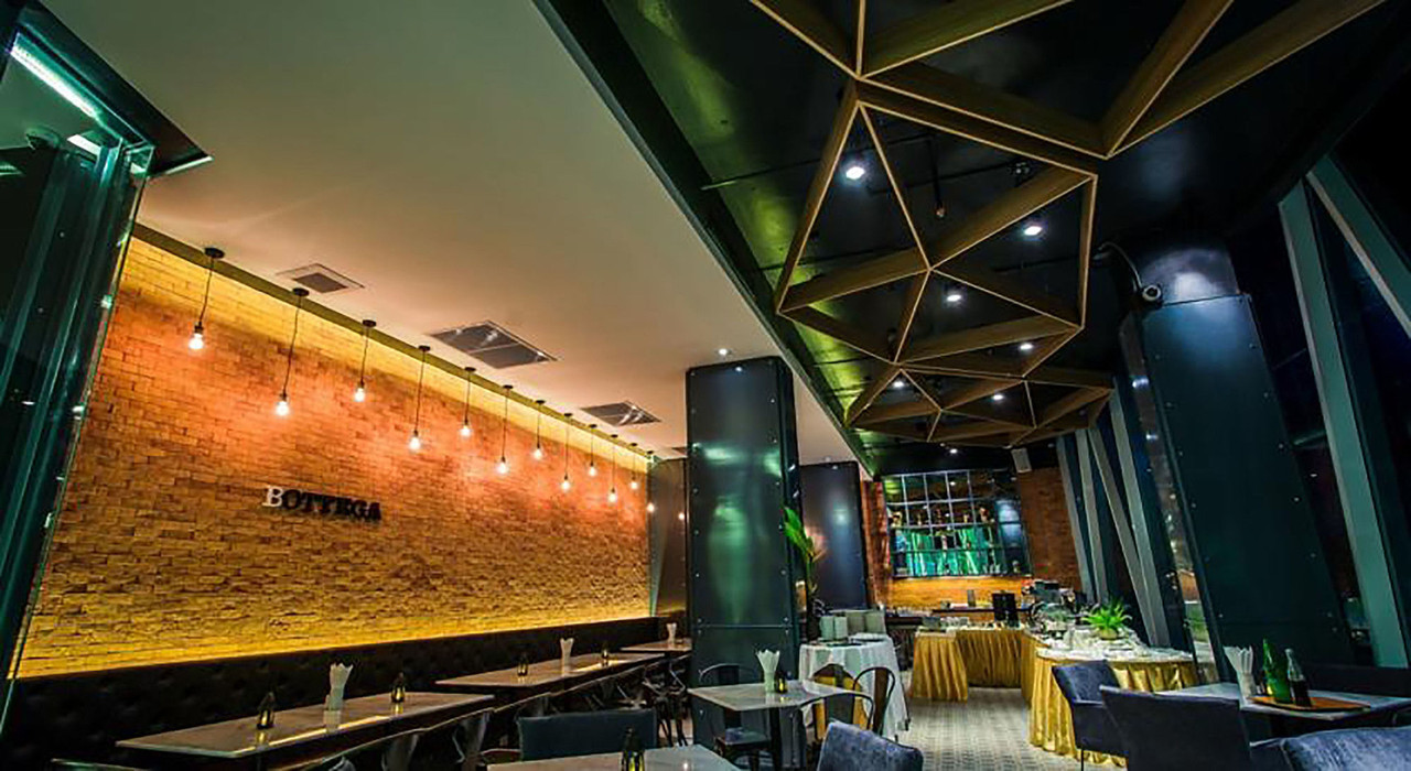 Bottega restaurant with exposed brick and a geometric timber ceiling at Crystal Hotel Hat Yai