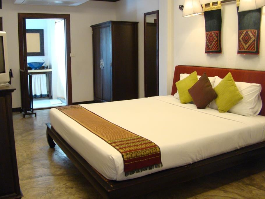 Guest room with a low teak bed and hill-tribe textile wall hangings