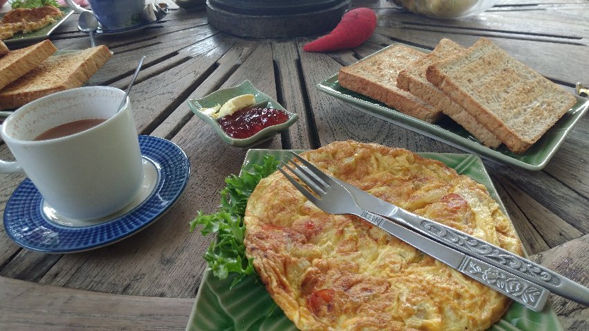 Breakfast of Thai omelette, toast and brewed coffee on a wooden table