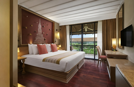 Thai-style guest room with a gold Sukhothai-stupa motif headboard and a private balcony over the garden