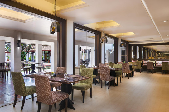 Lotus restaurant opening onto the garden, terracotta lamps and green upholstered chairs