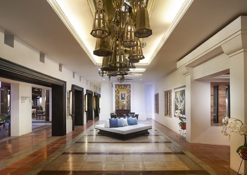 Lobby with terracotta-tile floor, a large brass chandelier and Thai artwork