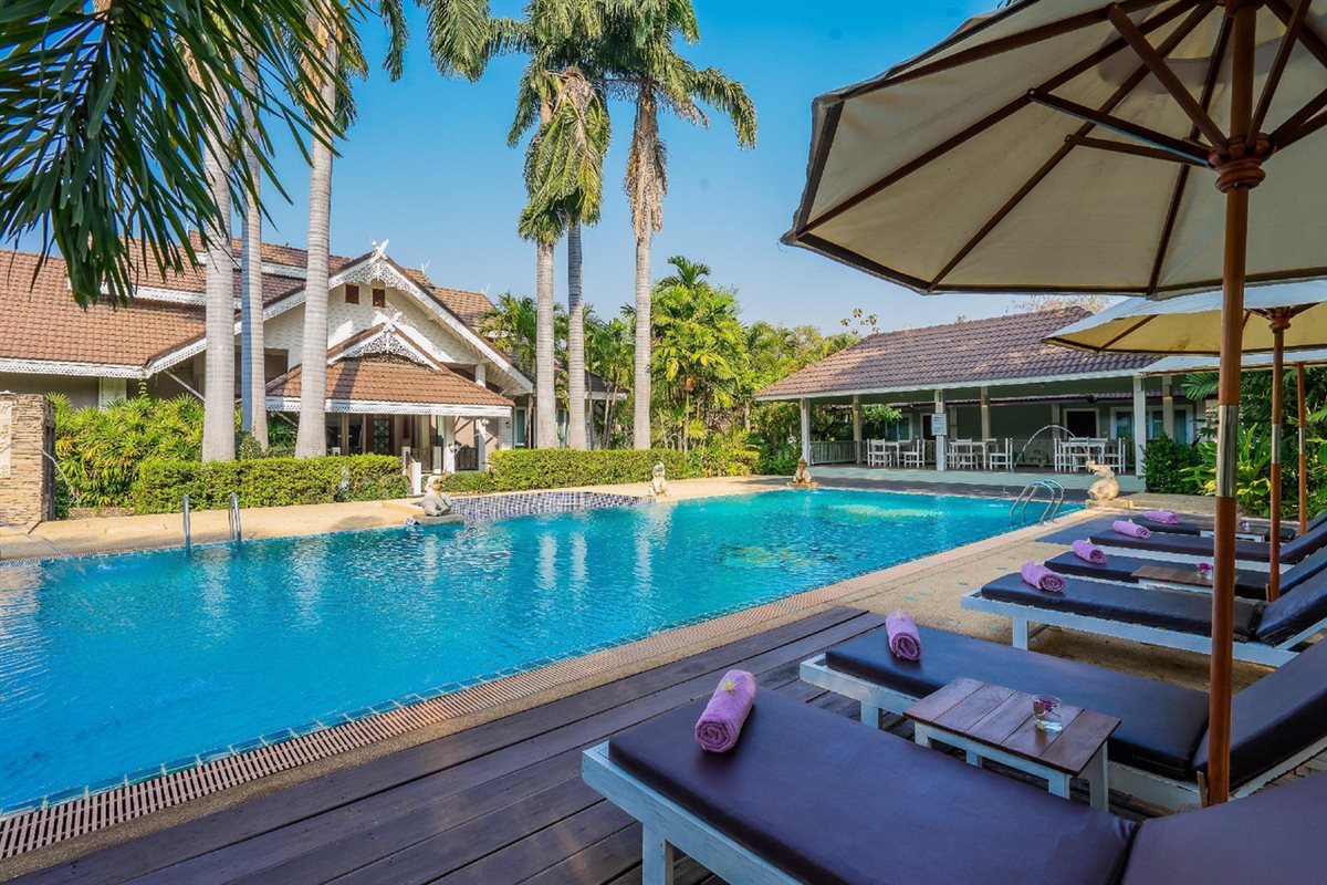 Outdoor pool at Le Charme Sukhothai with sun loungers along the deck