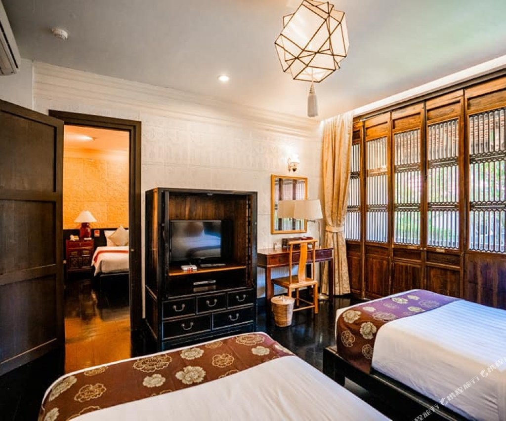 Tharaburi Resort guestroom with dark teak furniture and carved wooden lattice panels