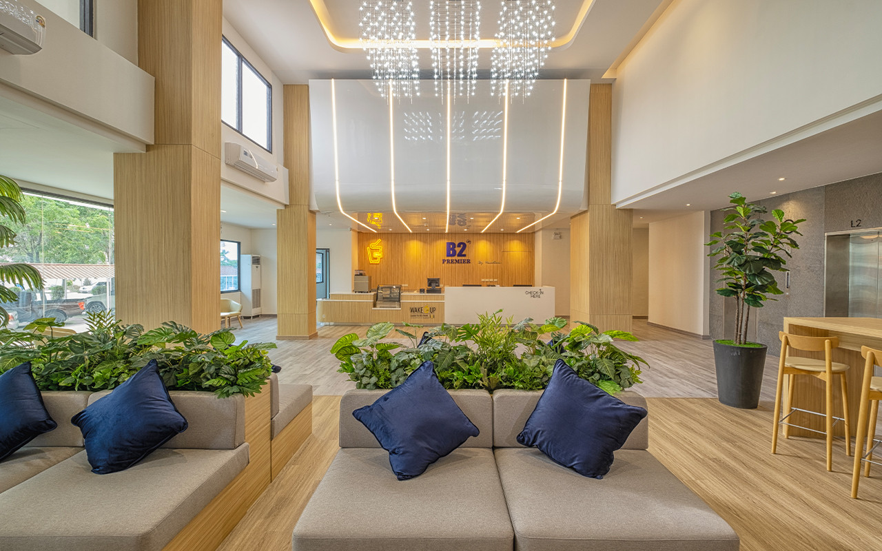 Lobby lounge corner at B2 Suphan Buri Premier with grey sofas, navy cushions and green plants