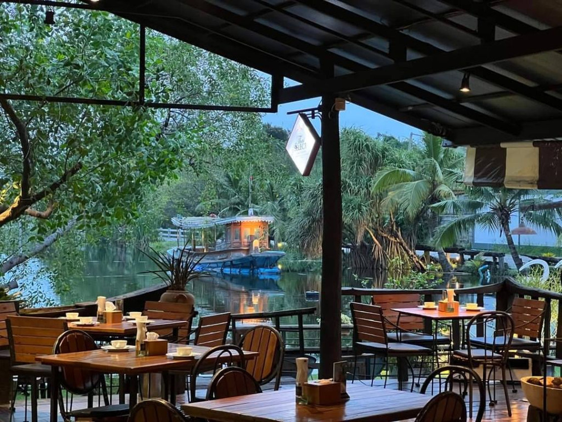 Lainam restaurant timber deck over the lake, wooden tables and water view at dusk