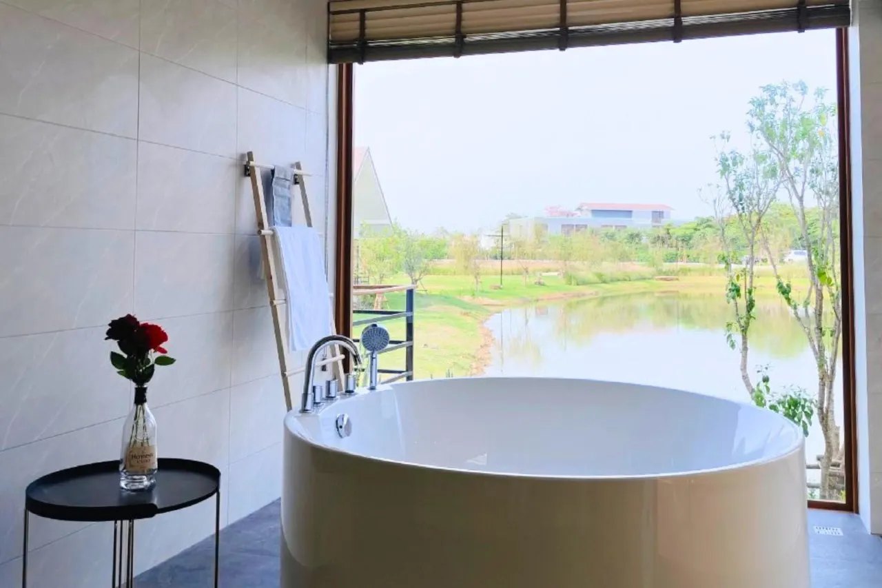 Round soaking tub facing a wide window with a lake view