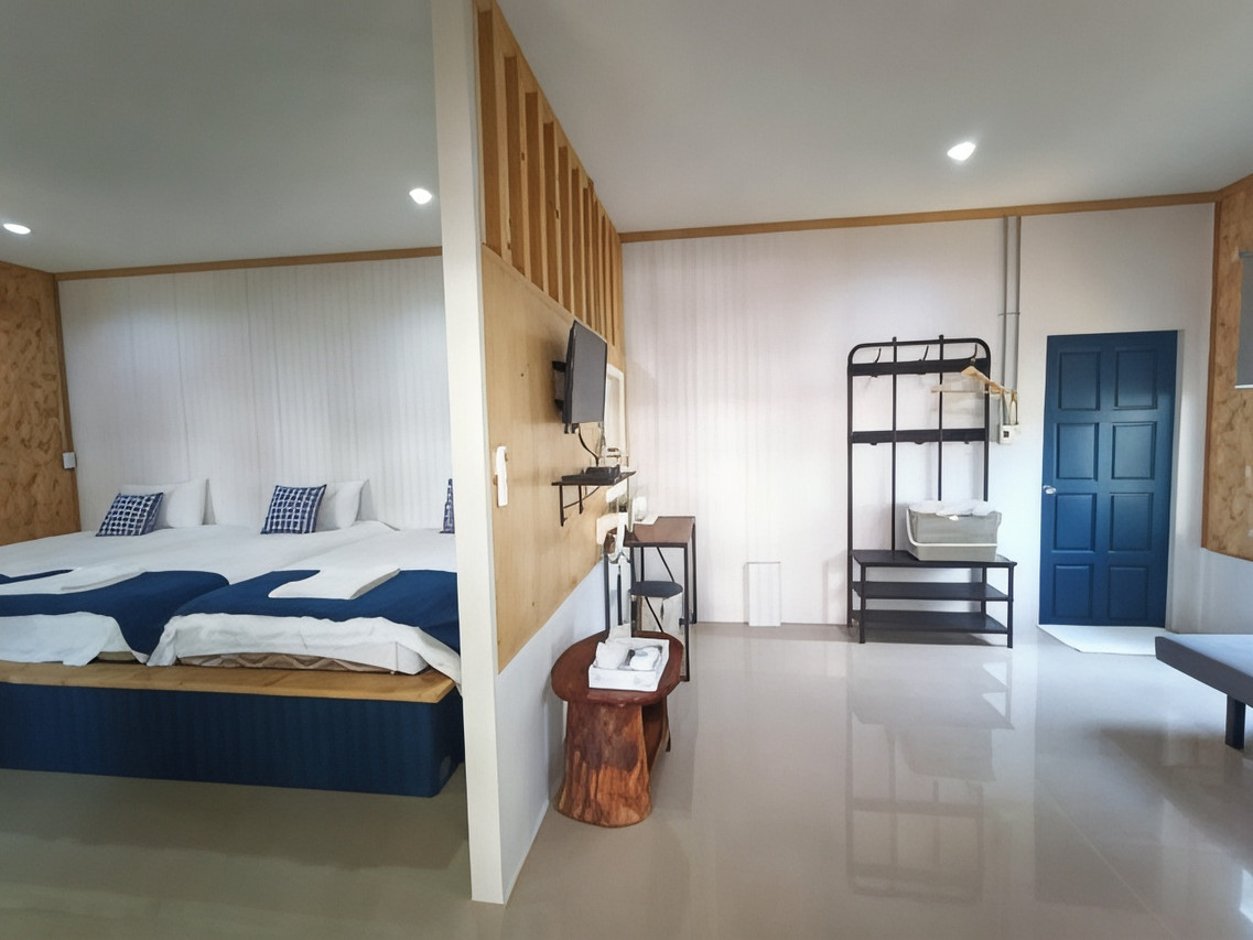 Lamoon Boutique Hotel guest room in white, navy and pine with a raised wooden bed base