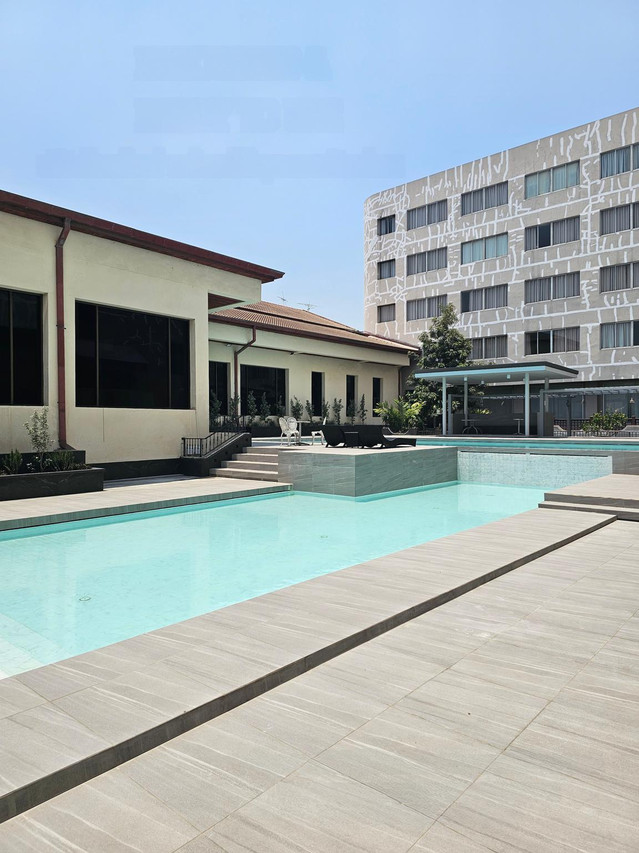 Outdoor pool at Songphanburi Hotel with the guest-room tower behind
