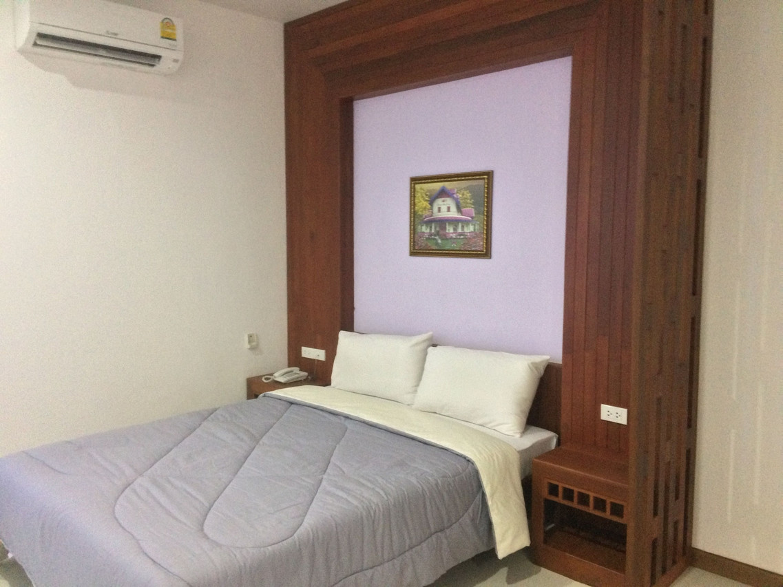 Second room type with a soft purple wall and a Thai-house painting above the bed