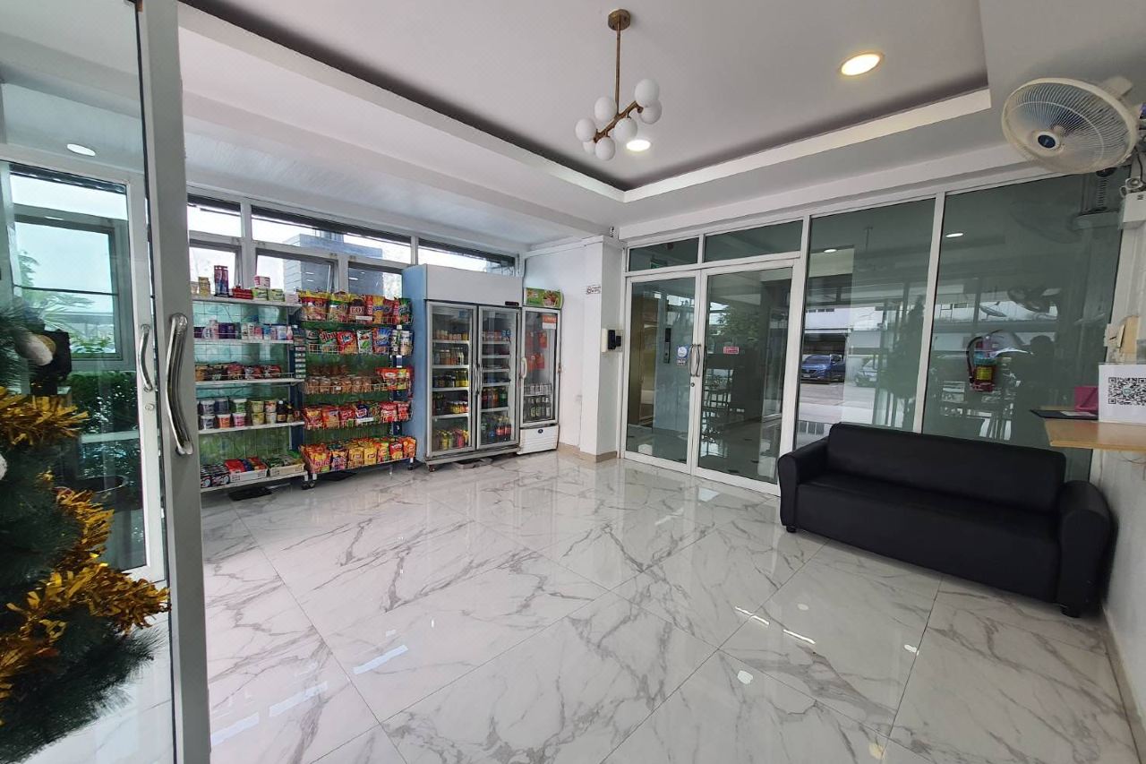 Ground-floor lobby with marble flooring, a small convenience shop with snacks and drinks, and a sofa