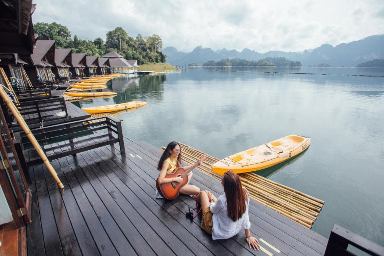 Row of wooden floating rooms at 500 Rai with yellow kayaks moored at the balconies