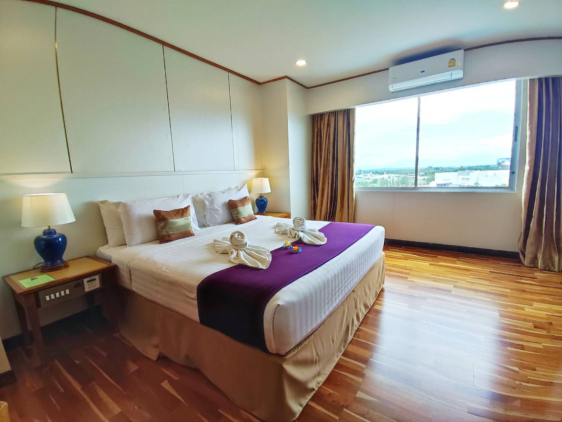 Guest room with parquet flooring and a city-view window over Surat Thani
