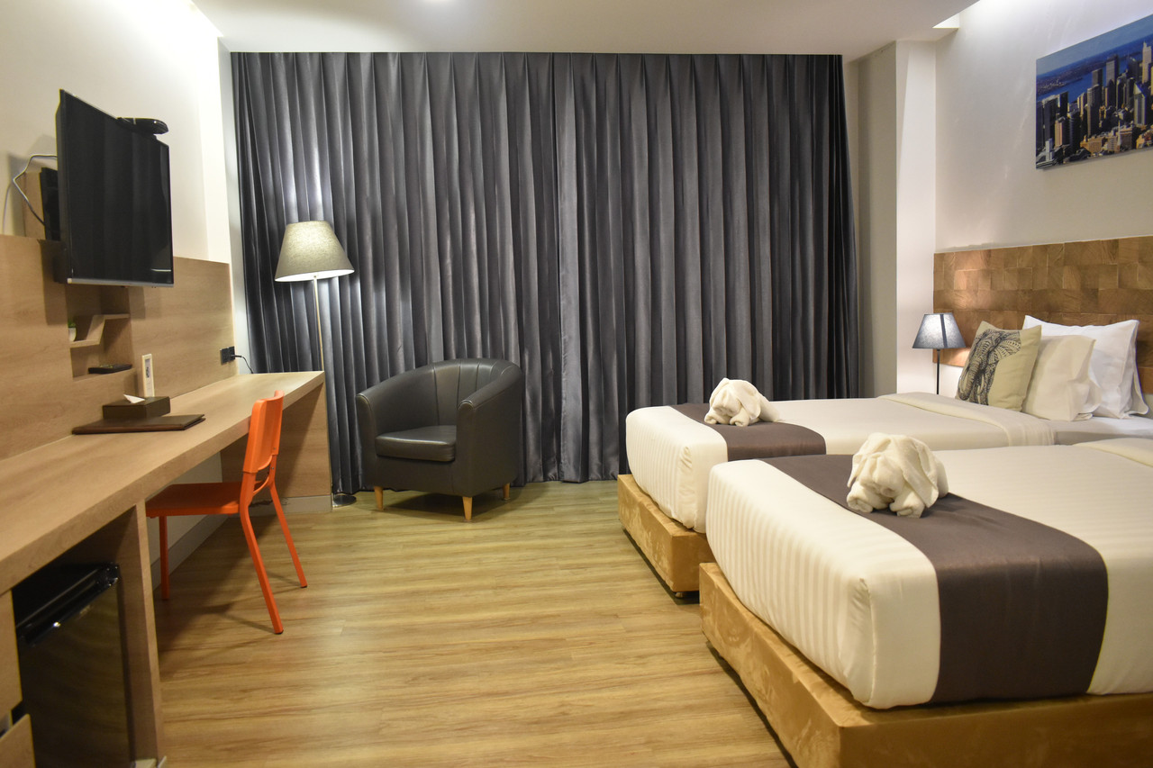 Deluxe Twin room with two beds, work desk and orange chair, in-room fridge