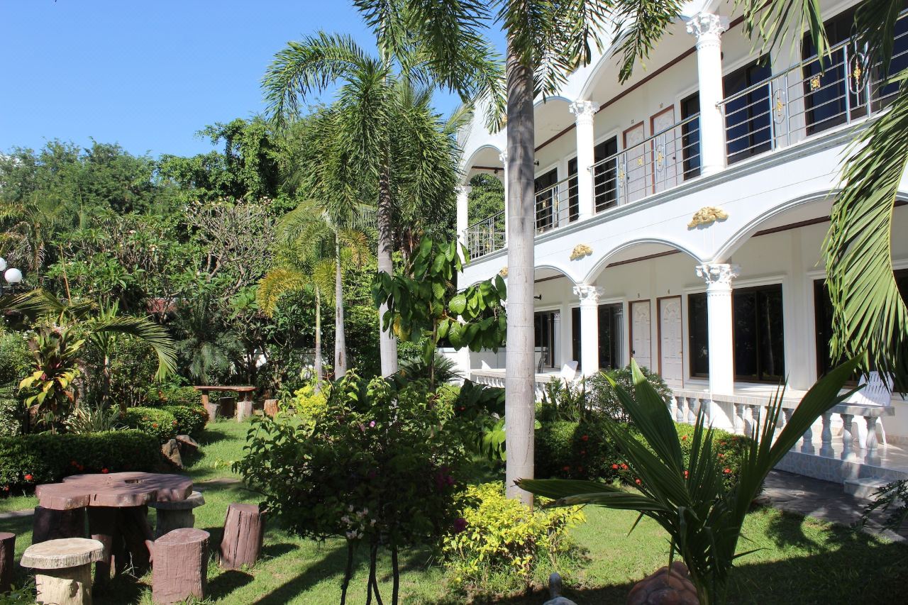 Front garden with palms and flowering plants and a stone garden table at the resort