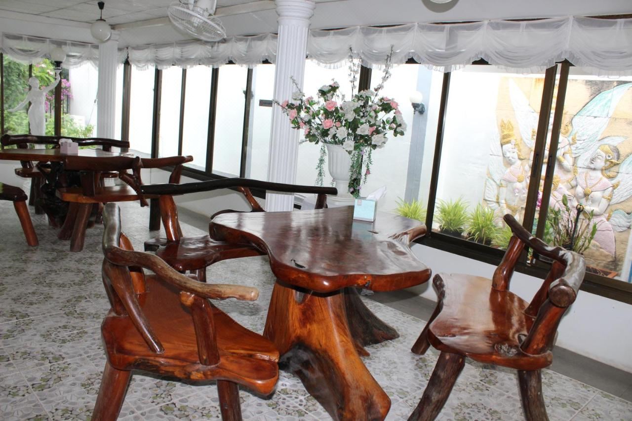 Indoor dining room with carved root-wood tables and chairs, white curtains and garden views all around