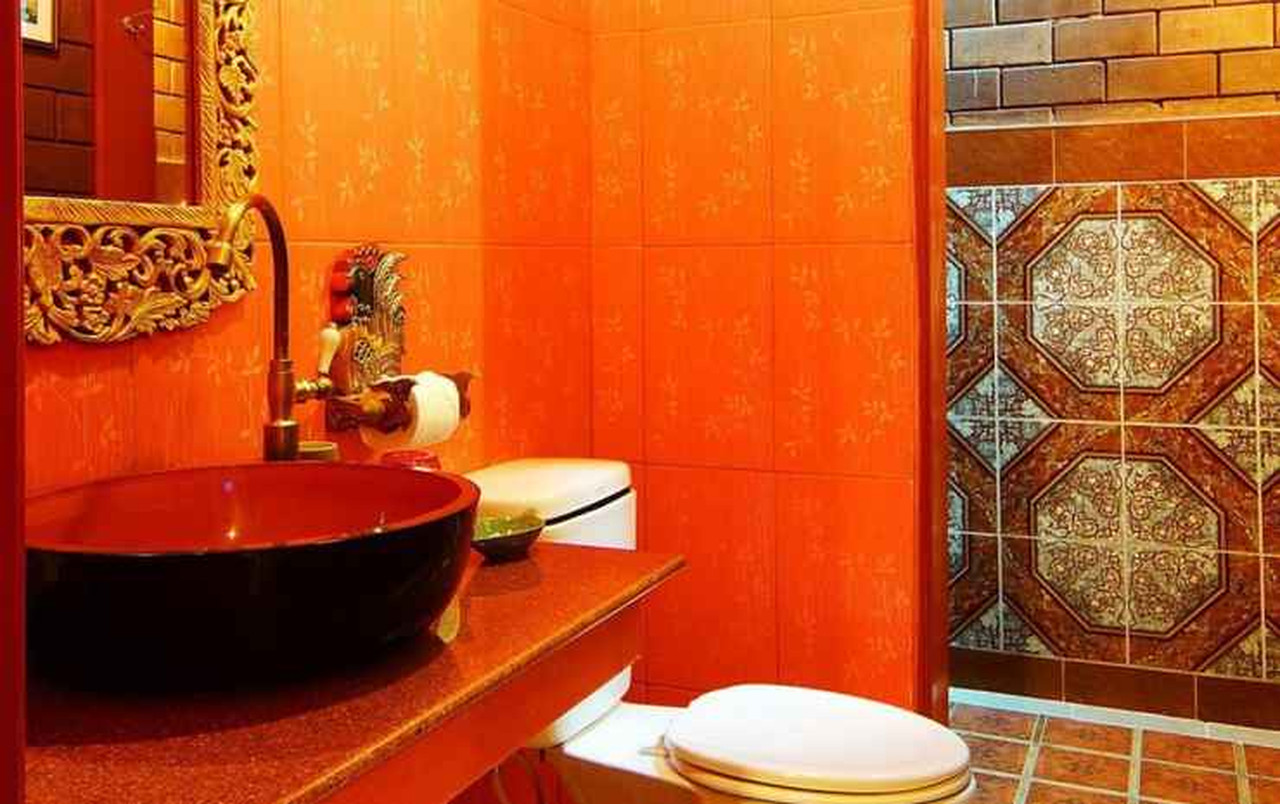 Burmese-style bathroom with orange-red patterned tiles and a round vessel basin