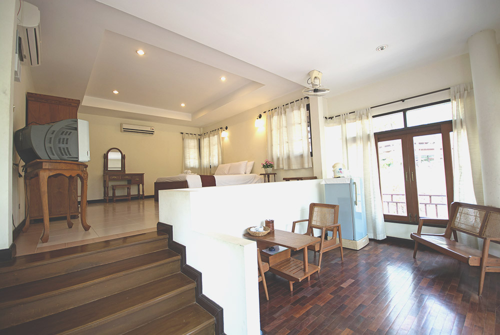 Spacious split-level villa interior with wooden floors and rattan sitting area at Tak Andaman Hotel