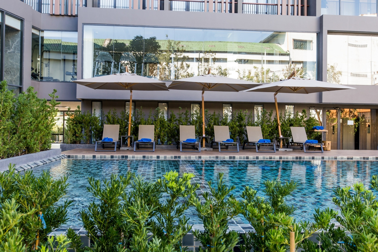 Outdoor pool with umbrellas and sun loungers at The Teak Hotel Mae Sot