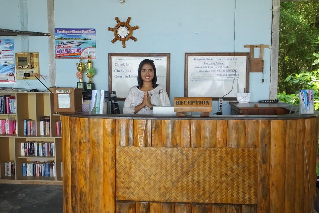 Wooden reception desk on Koh Kradan with a bookshelf and a boat-transfer timetable poster