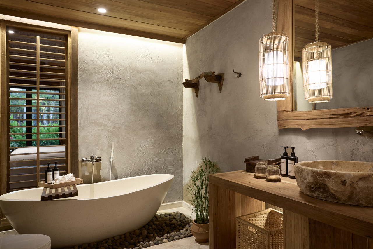 Natural-design bathroom with a freestanding tub, raw plaster walls and a timber ceiling