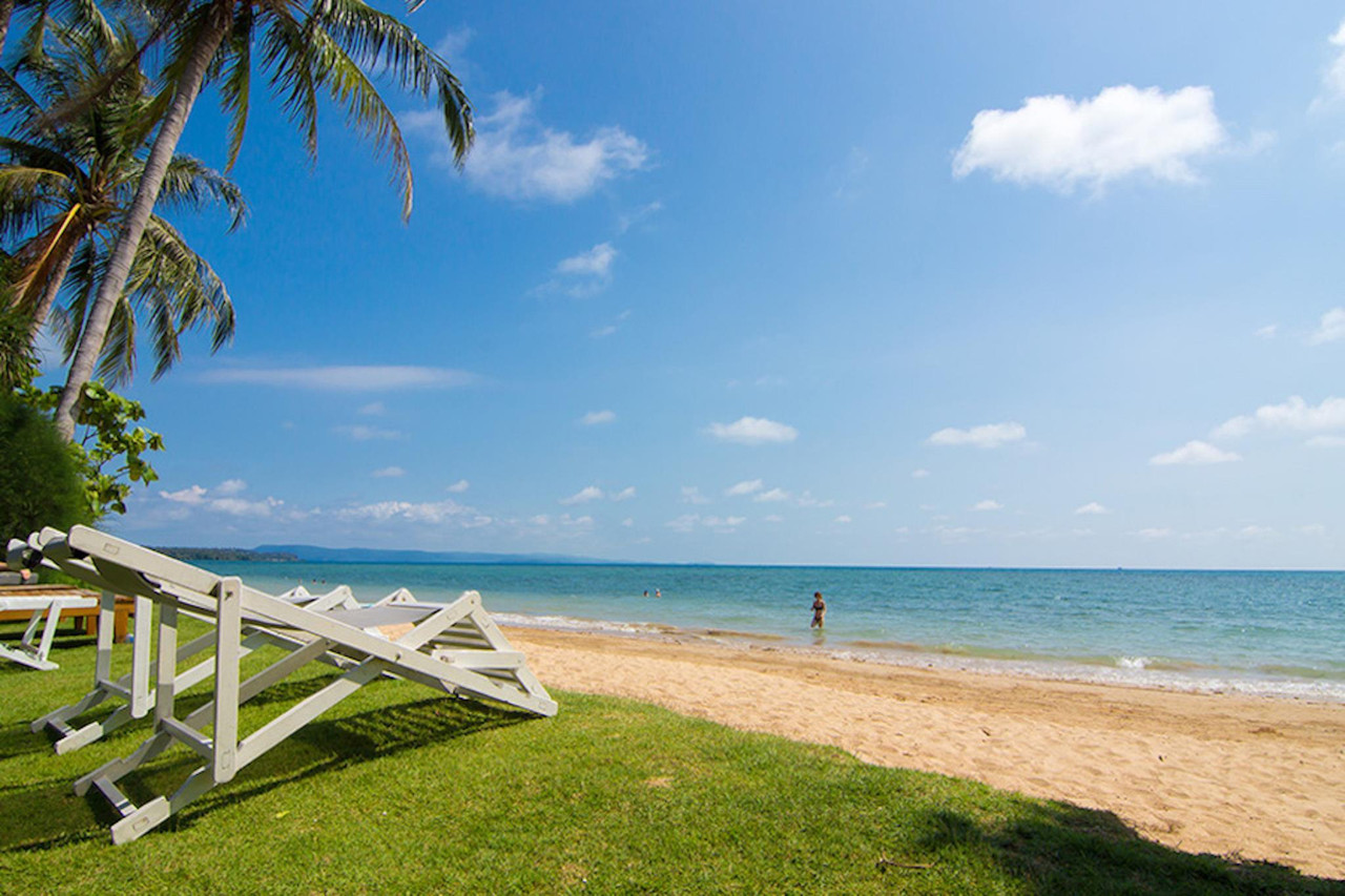 หาดอ่าวเกาะทรายขาวน้ำใสหน้า Makathanee Resort พร้อมเก้าอี้ผ้าใบบนสนามหญ้า