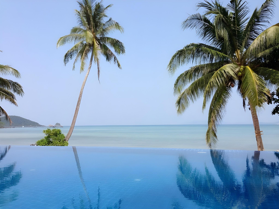 Beachfront swimming pool at Seavana with leaning coconut palms