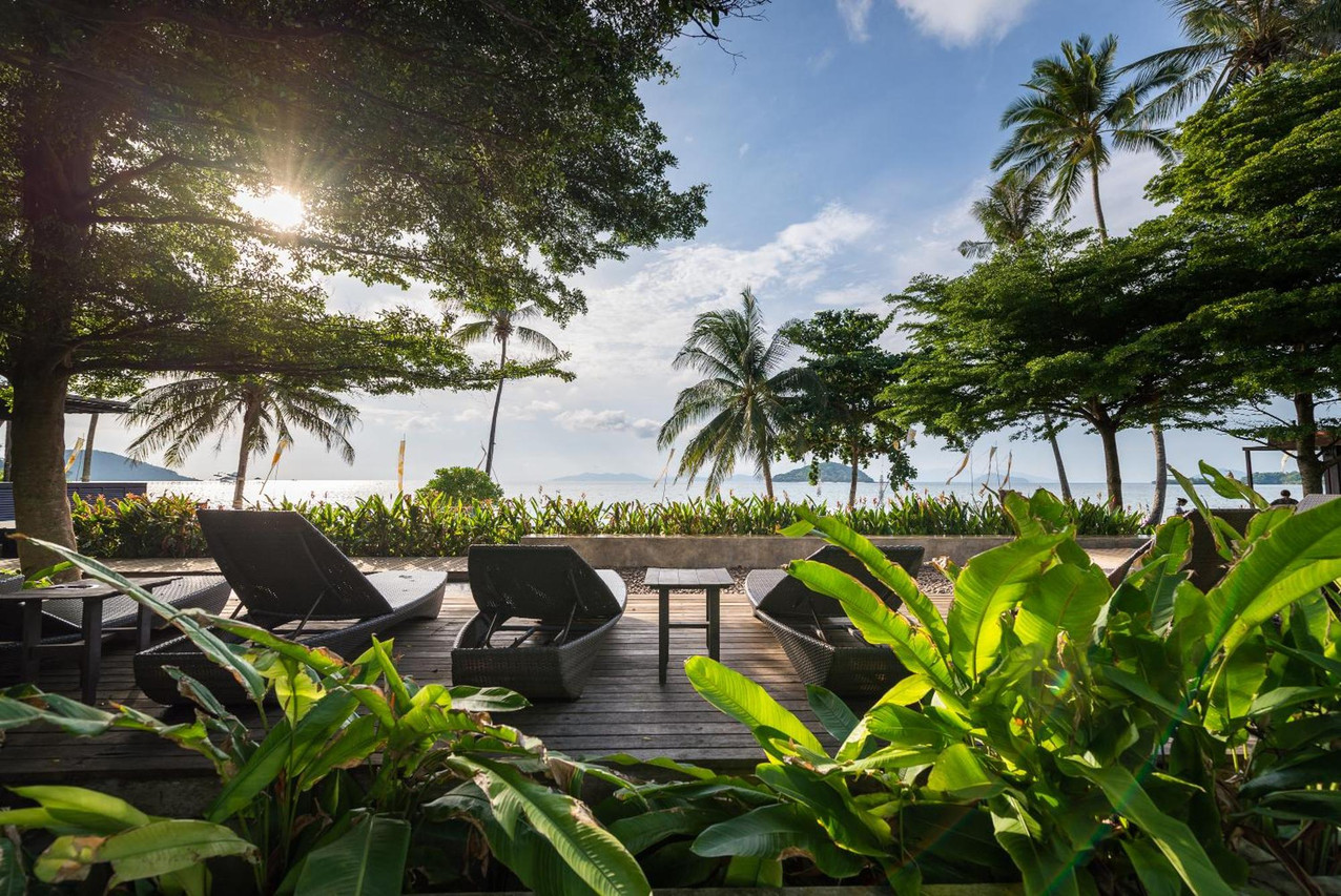 Sun loungers on a wooden deck beside Ao Suan Yai beach under coconut palms