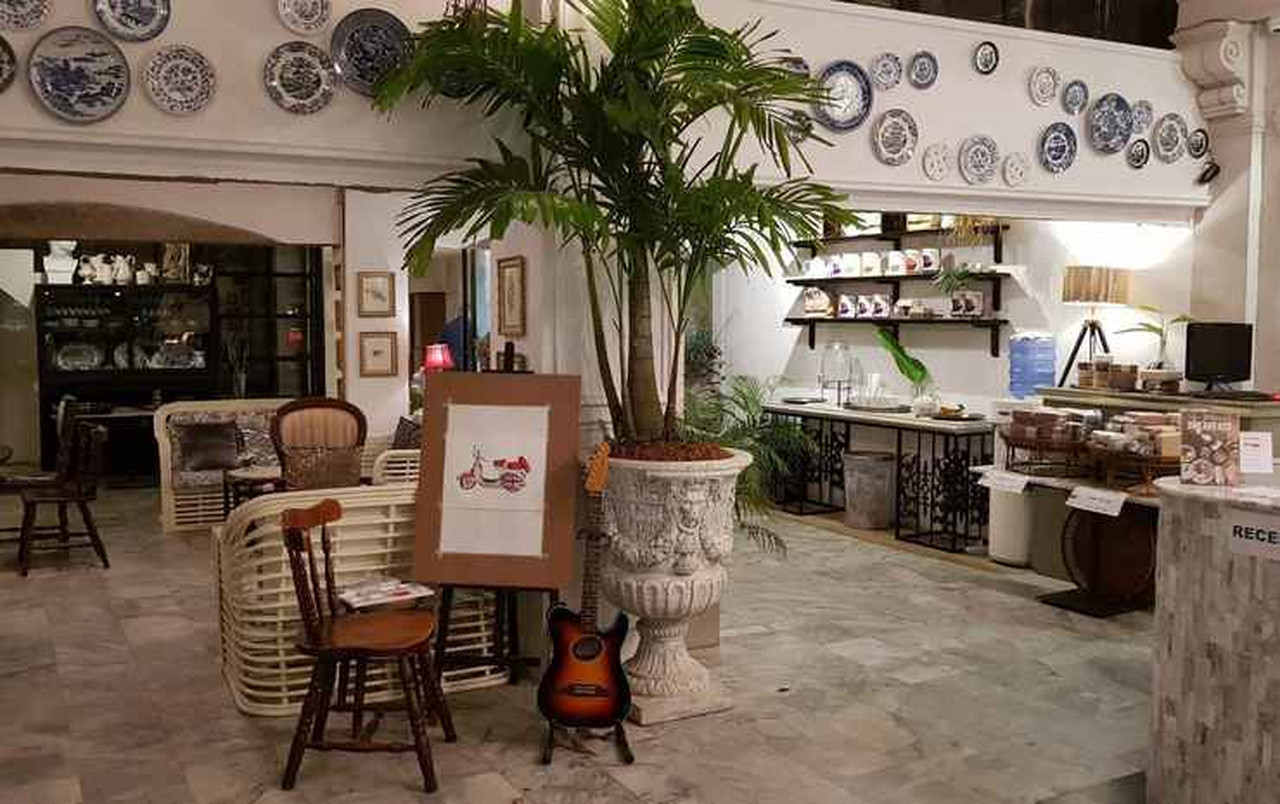 ล็อบบี้ Yuu Hotel แขวนจานลายครามบนผนัง มีเปียโนและมุมนั่งเล่นสไตล์ French-colonial