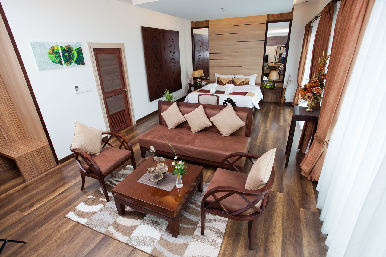Junior Suite with a separate sofa lounge area, wood floors and the bed behind