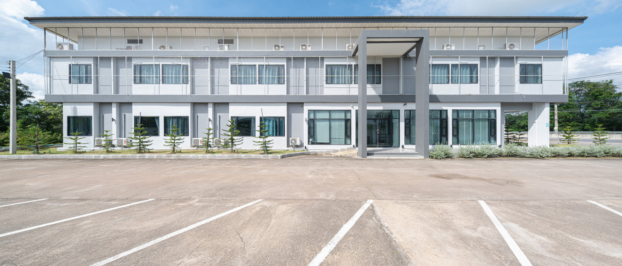 อาคารโรงแรม C2U Hotel Uthai Thani ตอนกลางวัน ตึกขาวเทากับลานจอดรถกว้าง