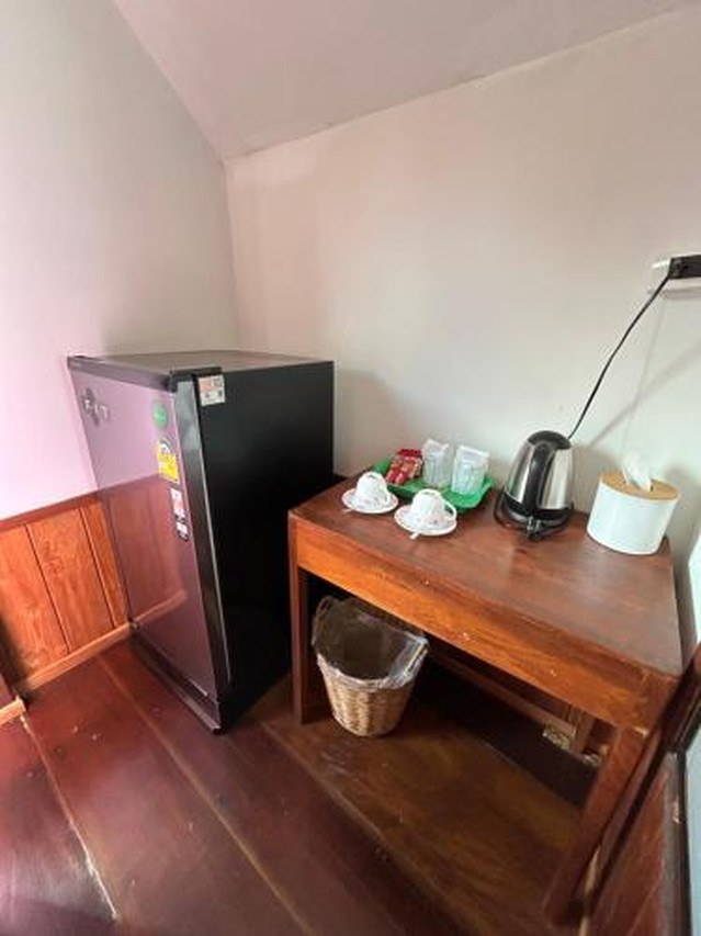 In-room corner with a fridge, wooden table, kettle and a coffee-and-tea set