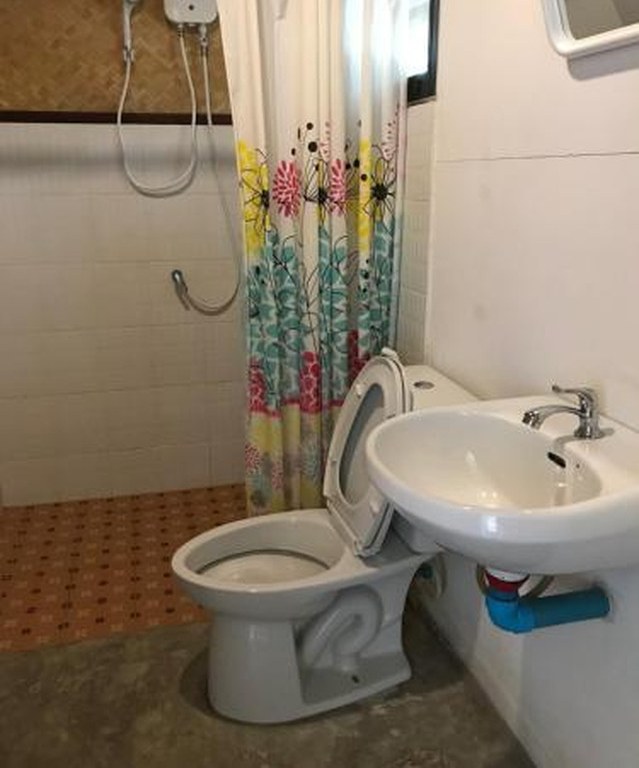 Guest bathroom with an electric water-heater shower and clean tiled walls