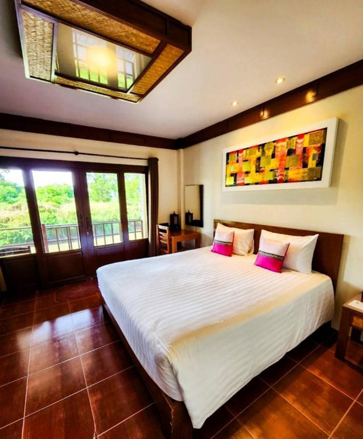 Deluxe room with a Thai woven-timber ceiling and a balcony overlooking the river