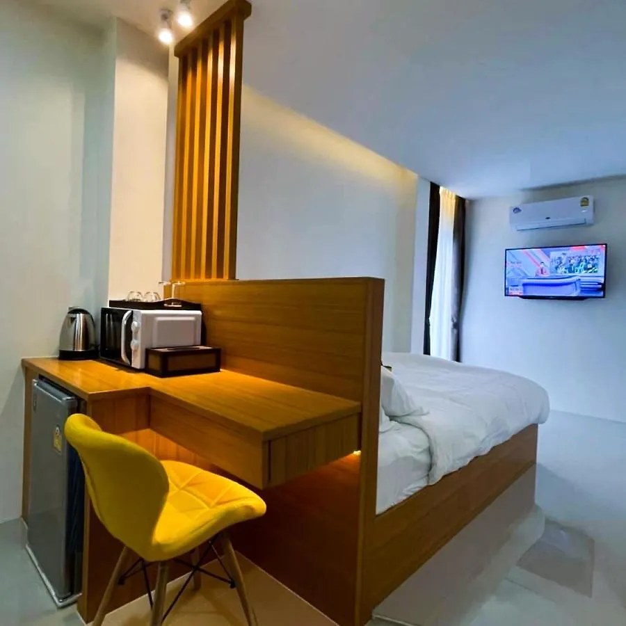 Guest room at TJ Boutique Hotel Uthai Thani with bed, wooden desk, mini-fridge and yellow chair