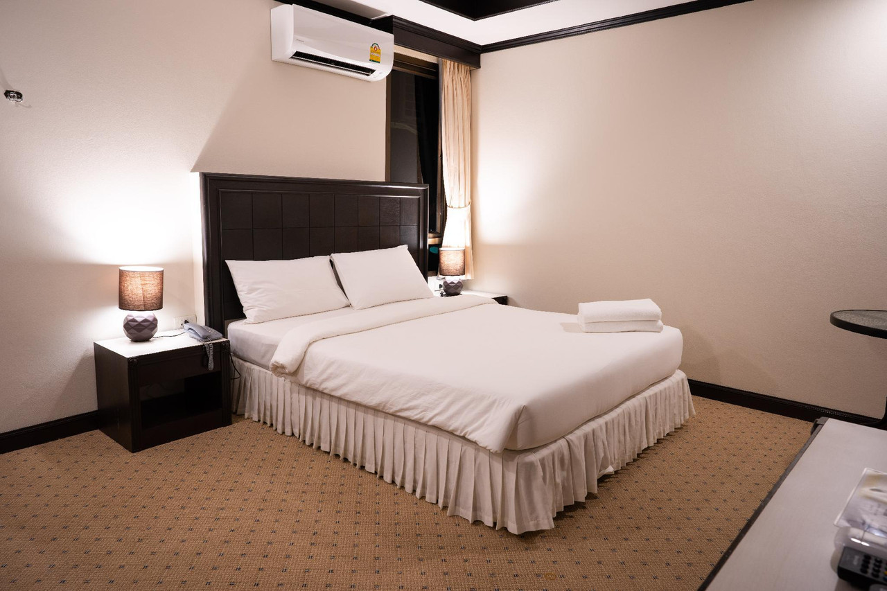 ห้องพัก Betong Hello Hotel เตียงใหญ่ หัวเตียงไม้สีเข้ม แอร์ติดผนัง และพรมลายจุด