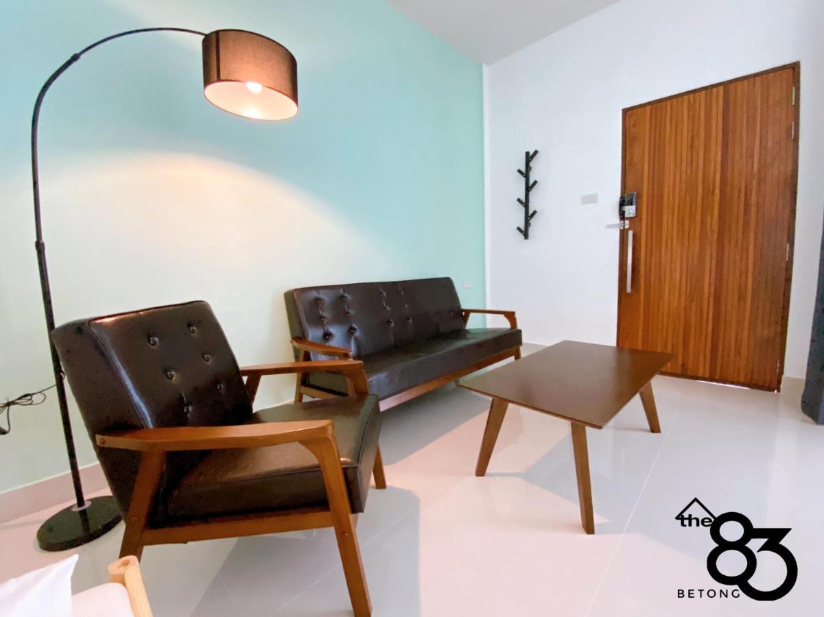In-room seating corner with a brown leather sofa, wooden chair, coffee table and the 'the 83 Betong' logo on the wall